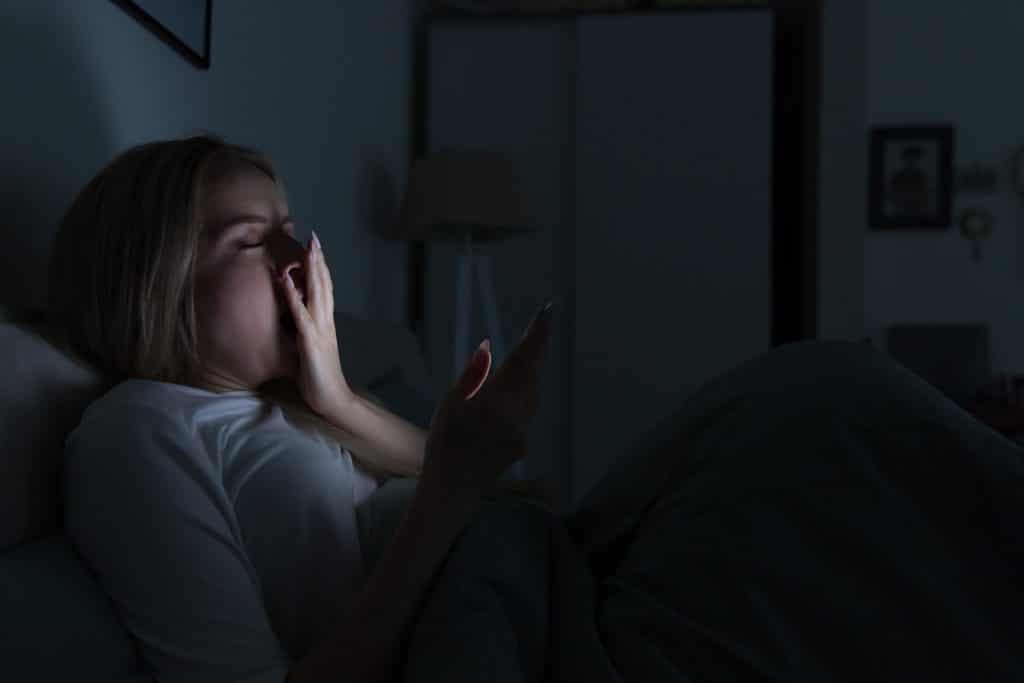Junge Frau kann nicht schlafen und ist am Smartphone
